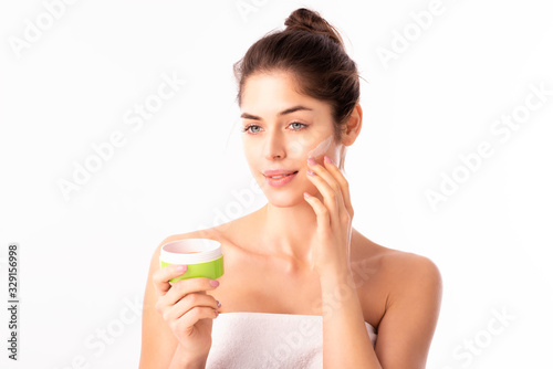 Young woman applying cream onto her face