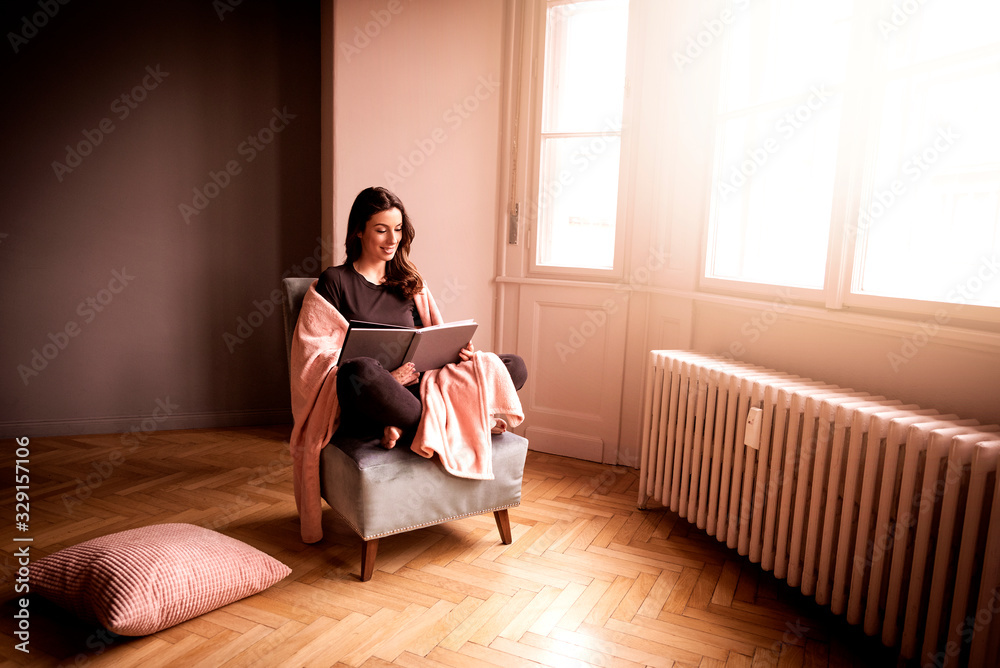 Relaxed woman reading a book at home - obrazy, fototapety, plakaty 