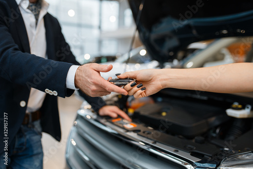 Man and salesgirl choosing auto in car dealership