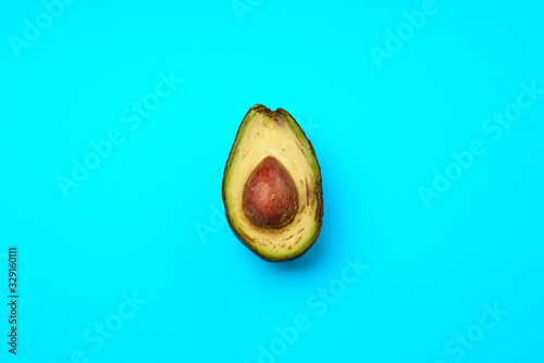 A rotten avocado cut in half on blue background. Avocado is rotten and no longer good to eat.