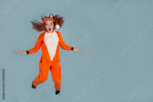 Fototapeta Naklejka Na Ścianę i Meble -  girl in plush kigurumi pajamas on a gray background, Fox costume