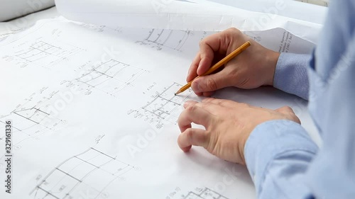 An engineer works in an office with blueprints. 