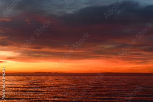 Orange sunrise over the sea. Dramatic sky clouds.