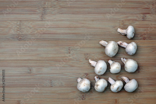 White mushrooms arranged in a triangle on the lower right of a bamboo board