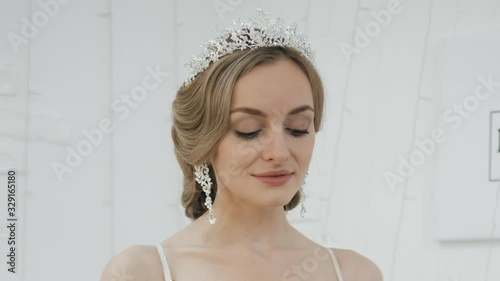 Close up shot of young blonde bride with gorgeous wedding hairstyle in tiara earrings turning head showing gorgeous wedding makeup and hairdo spinning around teasing and seductively looking in camera