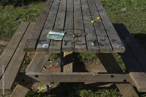 Barcelona, SPAIN, March 8, 2020: Plastic bags and bottles dumped in the park next to table contaminate environment
