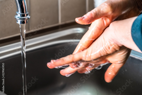 Proper washing of hands demonstrated at steel kitchen sink