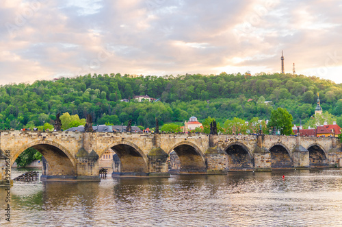 Charles Bridge Karluv Most with alley of dramatic baroque statues over Vltava river in Old Town of Prague historical center, garden on slope of Petrin Hill background, Czech Republic, Bohemia, Europe photo