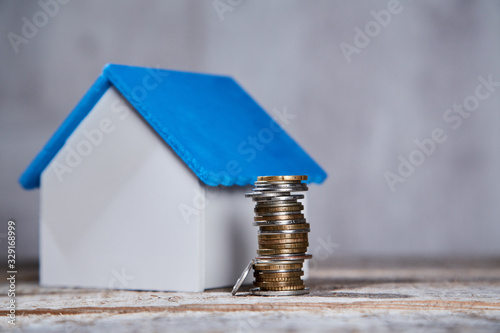 Buying or selling property. Real estate investment. Mortgage acquisition or rent house. Miniature home mockup with pile of coins. Blank copy space. photo
