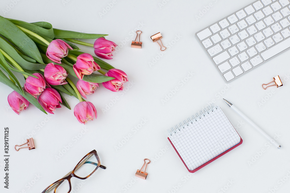 keyboard, paper clips, glasses, notebook, pen and bouquet of pink tulips keyboard, paper clips, glasses, notebook, pen and bouquet of pink tulips