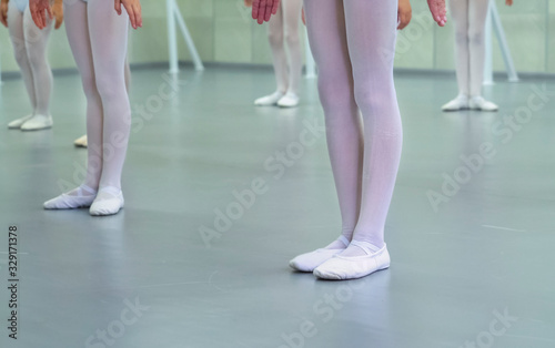 closeup legs of little ballerinas group in white shoes practicing in ballet school slow motion