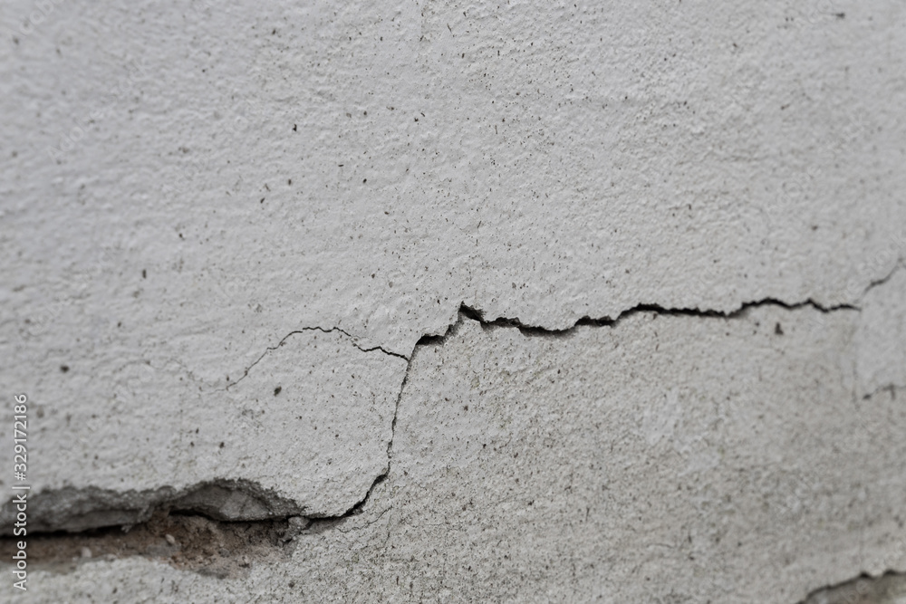 Obraz premium Old foundation and plaster wall with cracks. Building requiring repair closeup.