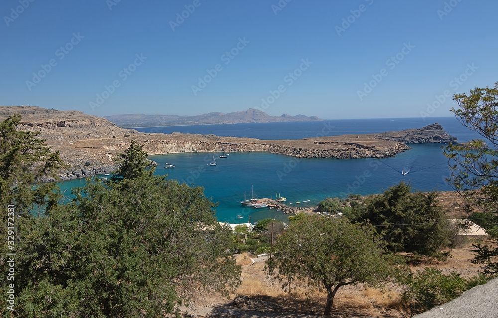 Obraz premium Panoramic view of the sea surface and the coast. View through the green of trees. Marine background Greece, Rhodes