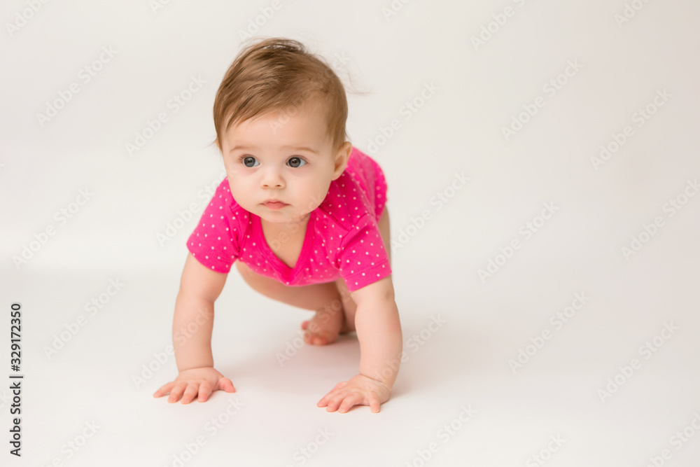 healthy baby girl in a pink bodysuit sits on a white background. space for text healthy baby girl in a pink bodysuit sits on a white background. space for text