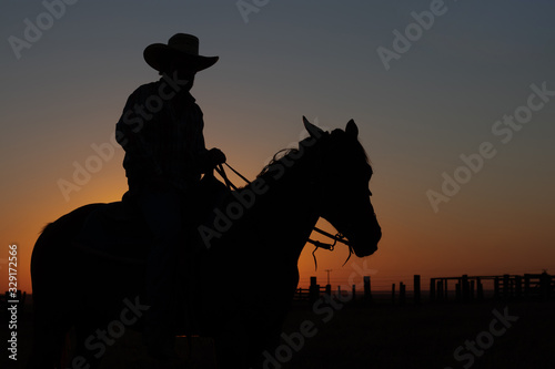 Homem fazendeiro montado no cavalo, por do sol, silhueta. photo