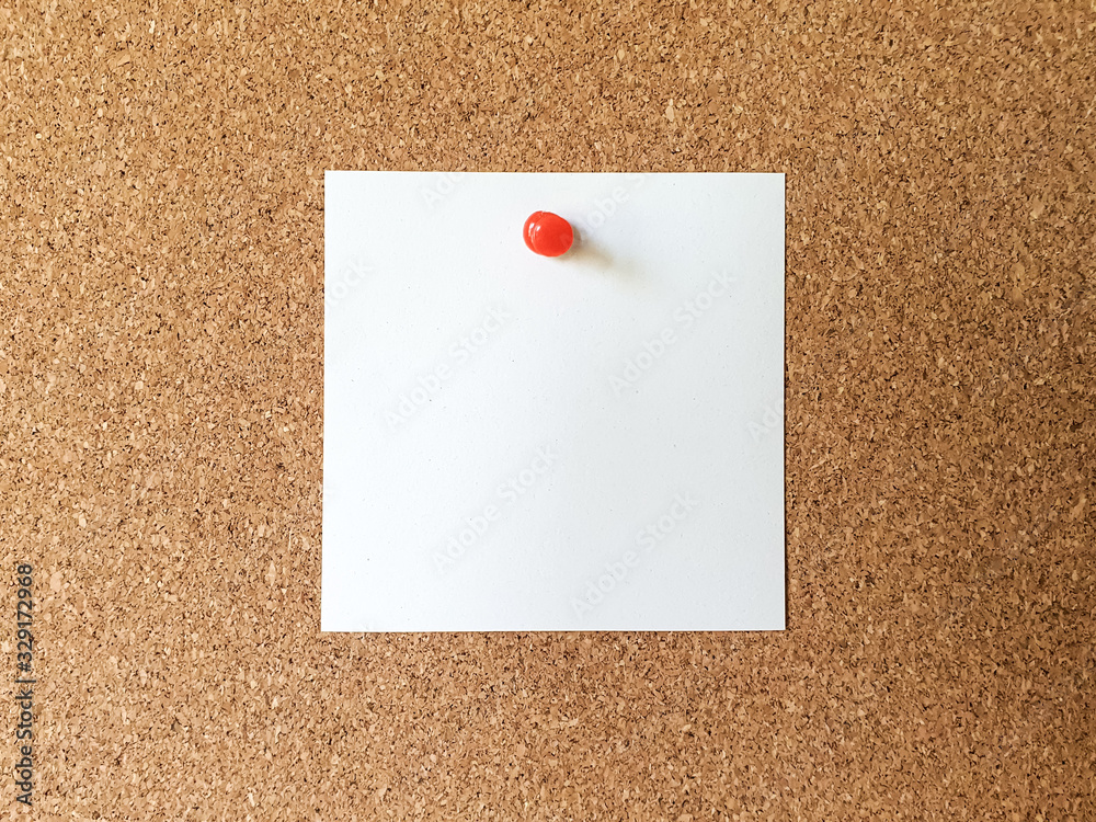 White note blank paper with red pin on empty cork board background White note blank paper with red pin on empty cork board background