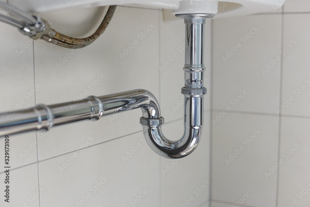 metal sink siphon and drain in white bathroom