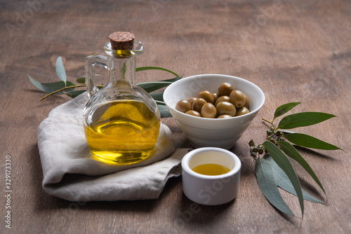 ripe natural eco friendly olives with olive oil in a bottle on a brown wooden background.