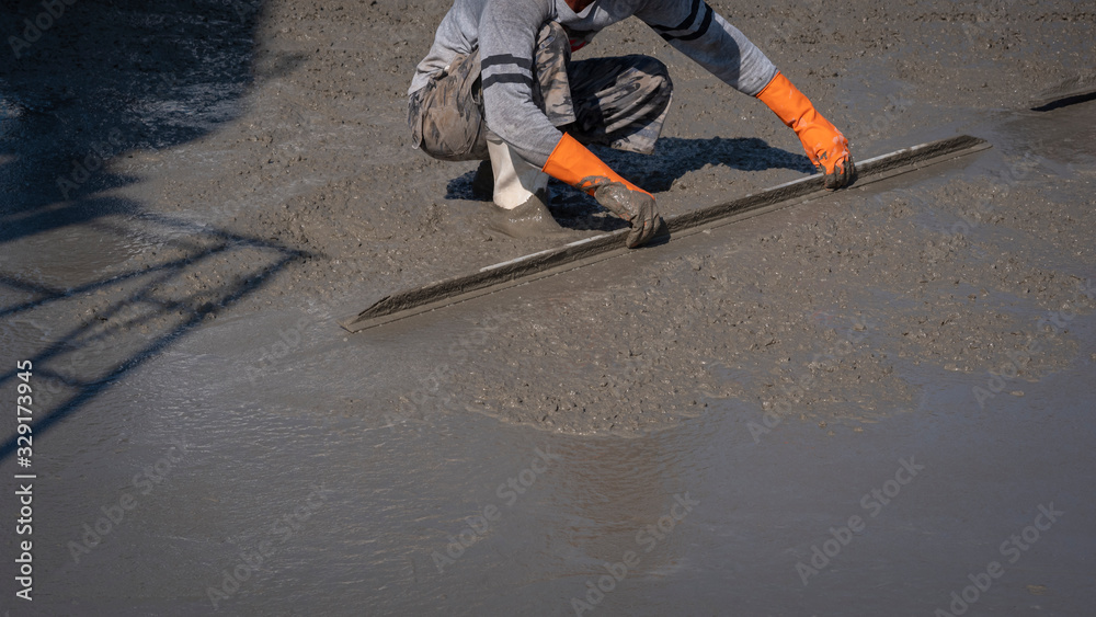 Cropped image of Asian construction worker using long triangle trowel to plastering cement on the floor