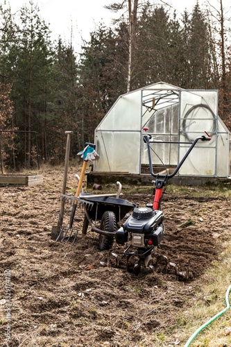  Agricultural work. Gardening. Spring preparation soil for seeding with tiller.  Spade, pitchfork and rake. Life on a small farm. photo