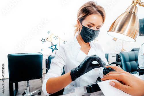 Manicure. Closeup portrait of a manicurist in a beauty salon. Manicurist is sawing a man’s client’s nails.