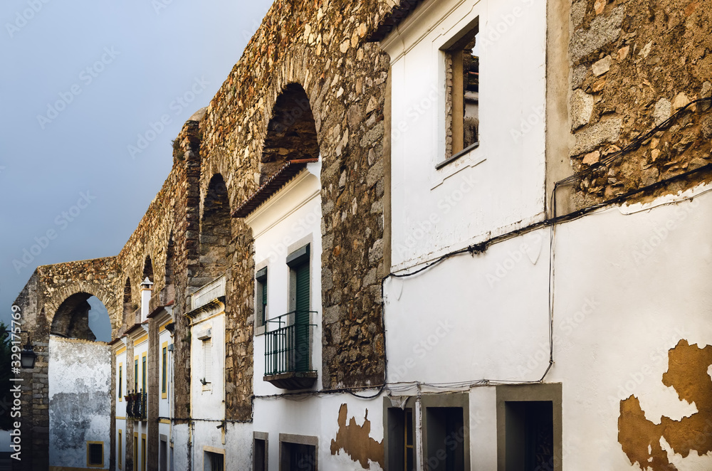 Houses in Evora (Alentejo, Portugal) along the ancient Agua da Prata aqueduct. Buildings were built during centuries directly between the arches of the aqueduct