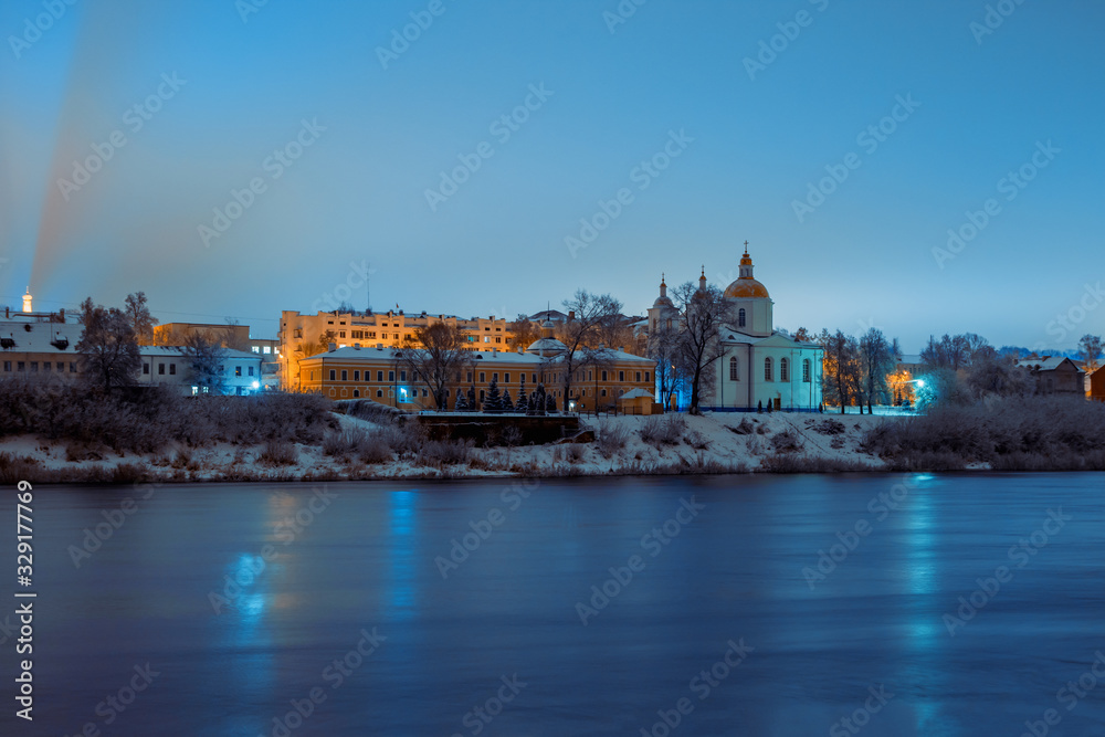 Obraz premium View across the river of the night city of Polotsk with the Epiphany Cathedral and reflection of lanterns in the river