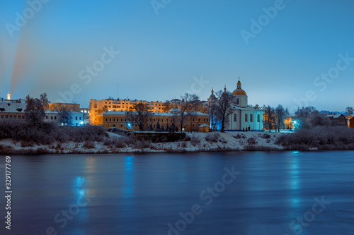 View across the river of the night city of Polotsk with the Epiphany Cathedral and reflection of lanterns in the river