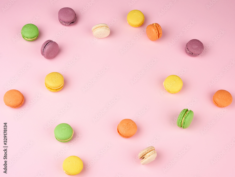 many multi-colored round baked macarons cakes on a light pink background many multi-colored round baked macarons cakes on a light pink background