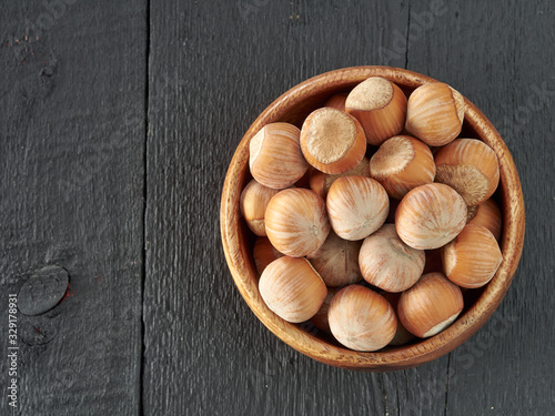 Hazelnuts lie in a plate on a black wooden background