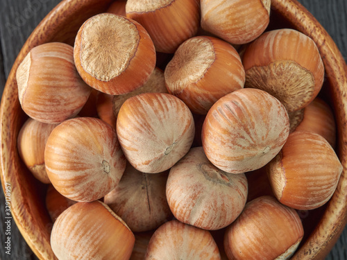 Hazelnuts lie in a plate on a black wooden background