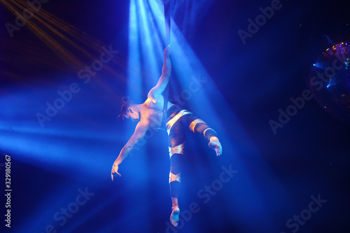 American strong sexy man do performance on aerial strap in blue lights. Sport training gym and lifestyle concept. Black background. 