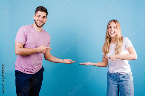 handsome couple man and woman pointing fingers at copy space on blue background