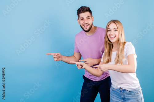 handsome couple man and woman pointing fingers at copy space on blue background