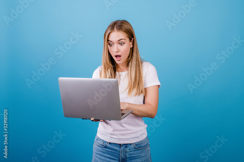 surprised pretty woman with laptop on blue background