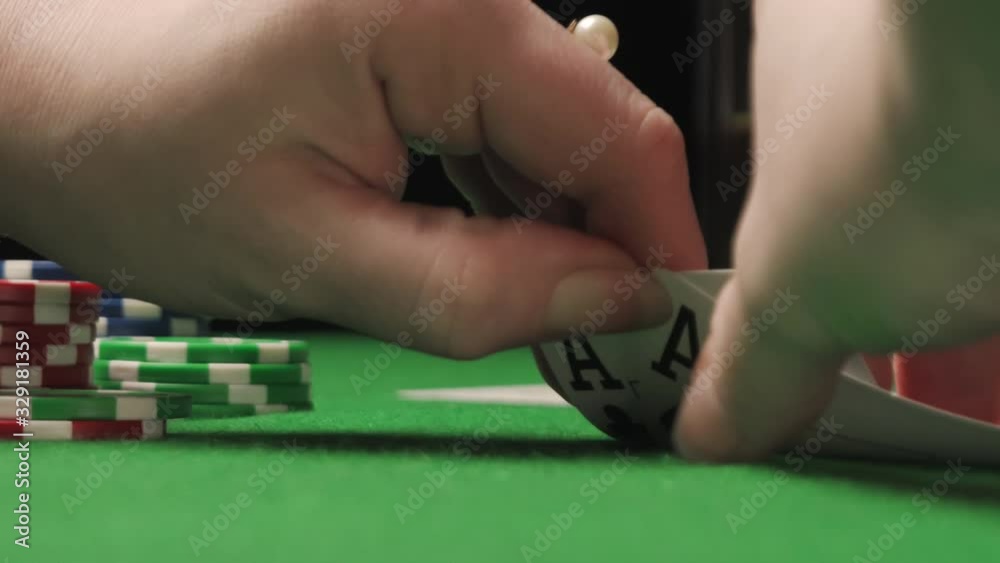 A woman poker player checking her hand, holding a pair of aces, winning game A woman poker player checking her hand, holding a pair of aces, winning game