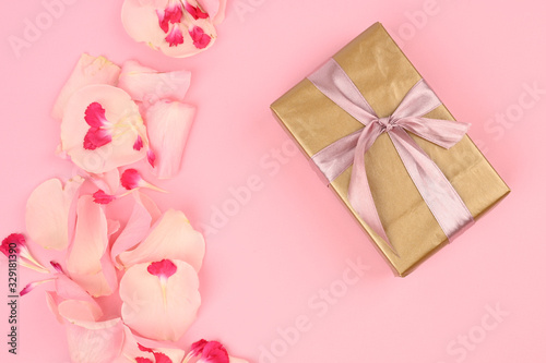 Flat lay composition with beautiful flowers and a gift box on a pink background. Space for text
