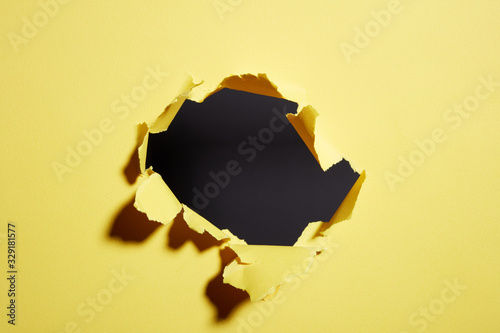 hole torn in the paper yellow background