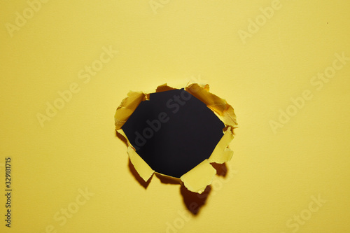 hole torn in the paper yellow background