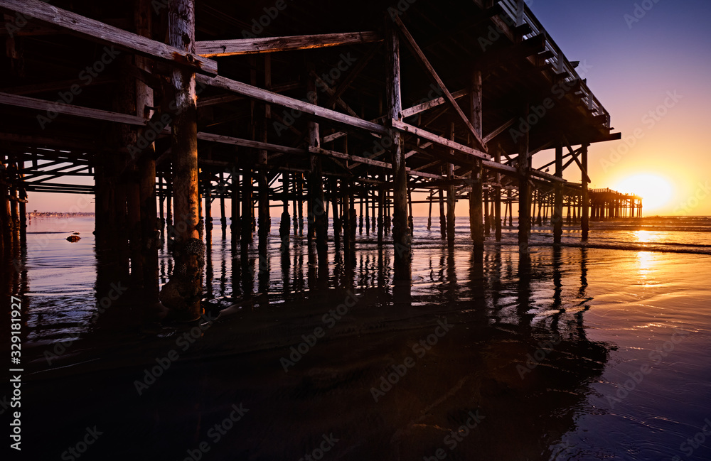 Barnacle-encrusted pilings of Crystal Pier at low tide on a sunny Winter evening