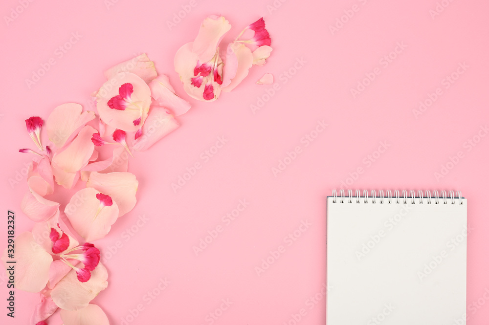 Styled flat lay mockup with floral elements on pink table. Copy space.