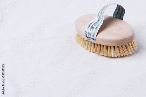Natural wooden brush for dry body brushing on a beige organic cotton fabric