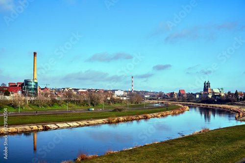 warta river, industrial chimneys and cathedral towers in city of Poznan.