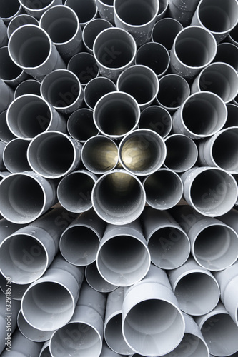 Gray PVC tubes plastic pipes stacked in rows with light shinning through