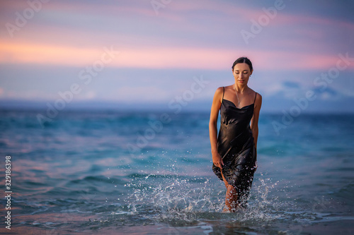 Beautiful woman by the ocean at sunset