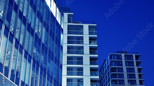 Night architecture - building with glass facade.Blue color of night lights. Modern building in business district. Concept of economics, financial. Photo of commercial office building exterior. Abstra