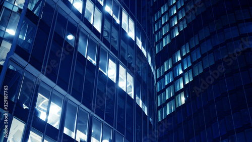 Night architecture - building with glass facade.Blue color of night lights. Modern building in  business district. Concept of economics  financial. Photo of commercial office building exterior. Abstra