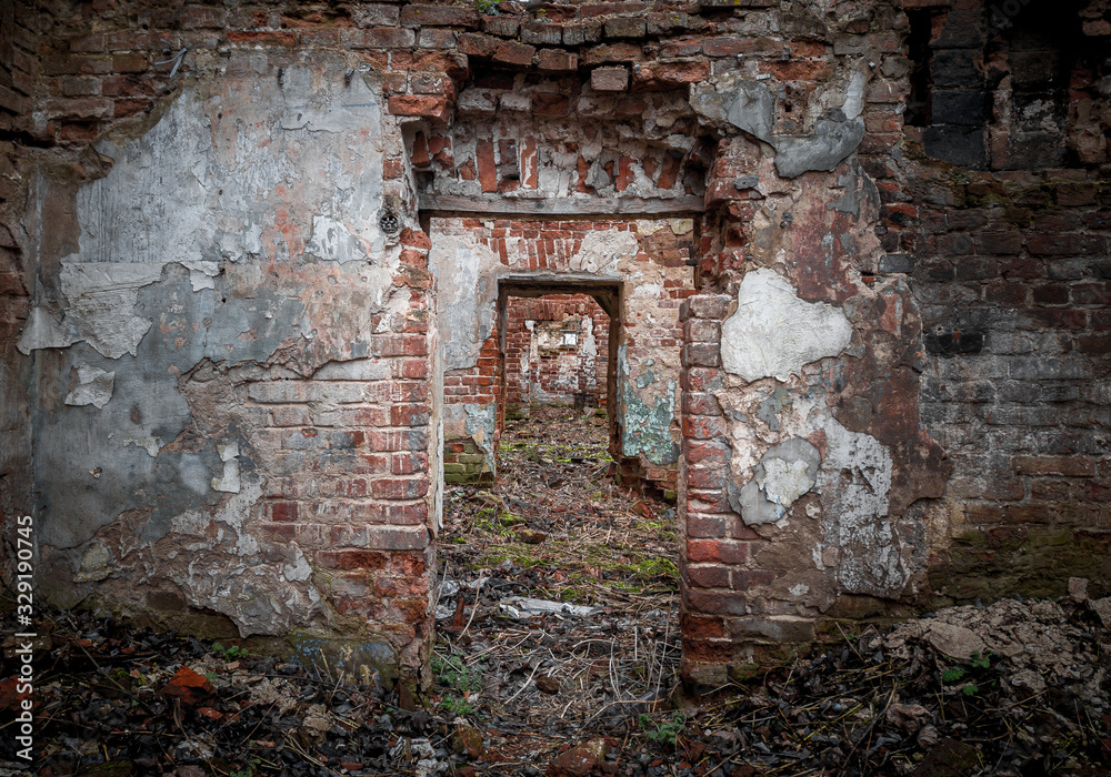 Inside of the mansion ruins. Red brick walls with empty portals. Perspective view of the several doorway,  located one after another inside desolated old building with dirt floor with green grass. 