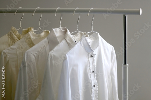 Collection of white shirts and blouses on a clothing rack. Selective focus.