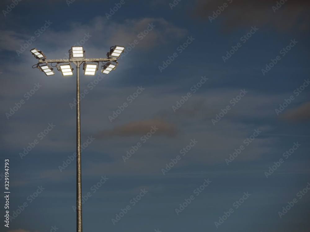 Powerful LED light on a metal pole turned on, cloudy sky background. Concept sport event, game. Powerful LED light on a metal pole turned on, cloudy sky background. Concept sport event, game.